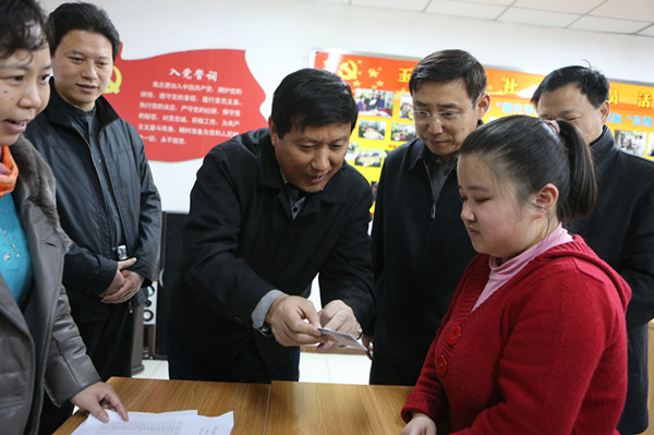 图为发卡现场，梁田巡视员向残疾人讲解用卡注意事项