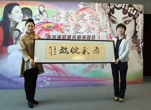图片为：市残疾人福利基金会秘书长李雪梅代表中国残疾人书法家联谊会会长、北京市肢残协会主席、北京市残疾人书画会会长刘京生先生向姜亦珊赠送书法作品